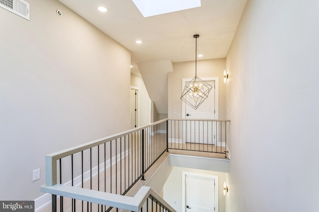 stairway featuring a skylight and a notable chandelier