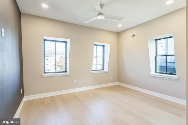 empty room with ceiling fan, a wealth of natural light, and light hardwood / wood-style flooring