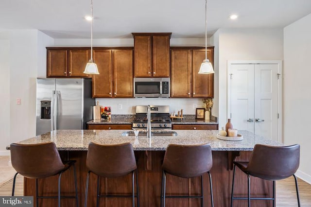 kitchen featuring a breakfast bar, stainless steel appliances, and an island with sink