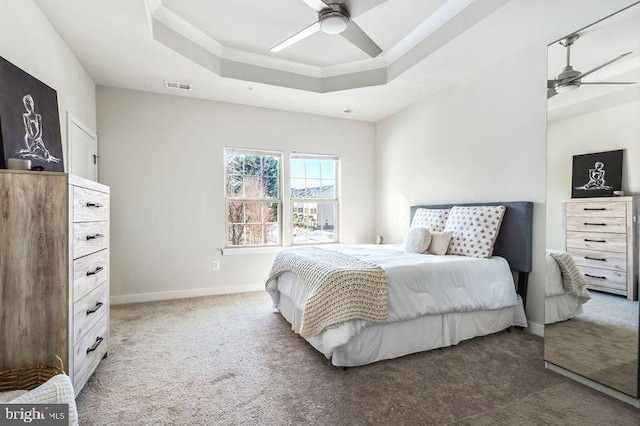 carpeted bedroom featuring ceiling fan and a raised ceiling