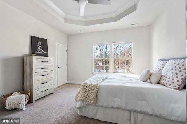 carpeted bedroom with ceiling fan and a tray ceiling