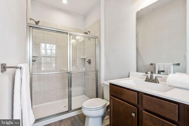 bathroom featuring hardwood / wood-style floors, toilet, walk in shower, and vanity