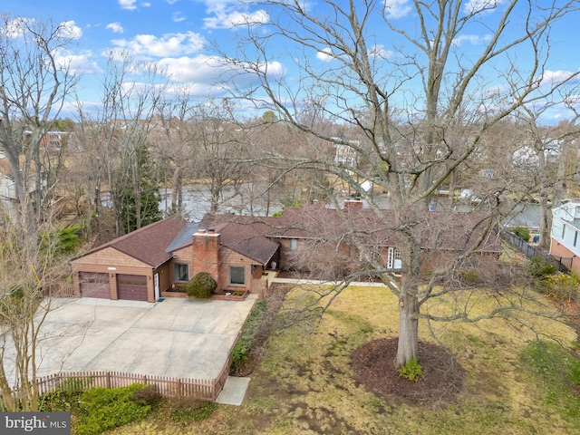 view of front facade with driveway, a chimney, an attached garage, fence, and brick siding