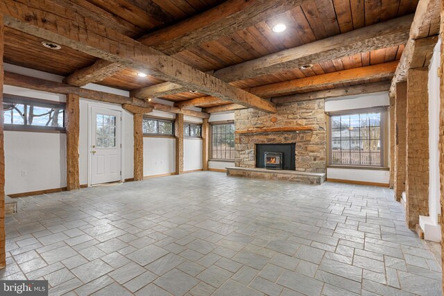 unfurnished living room featuring baseboards, wooden ceiling, and a healthy amount of sunlight