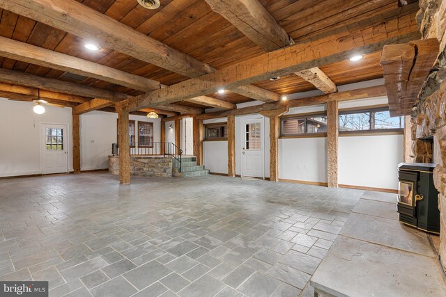 unfurnished living room with wooden ceiling, stone tile floors, stairway, beam ceiling, and a wood stove