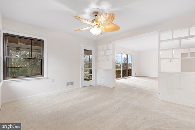 empty room with baseboards, carpet floors, visible vents, and a ceiling fan