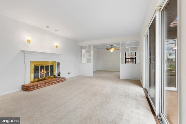 unfurnished living room with a brick fireplace, carpet, and ceiling fan