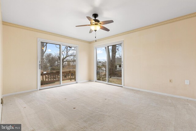 carpeted spare room with ornamental molding, ceiling fan, and baseboards