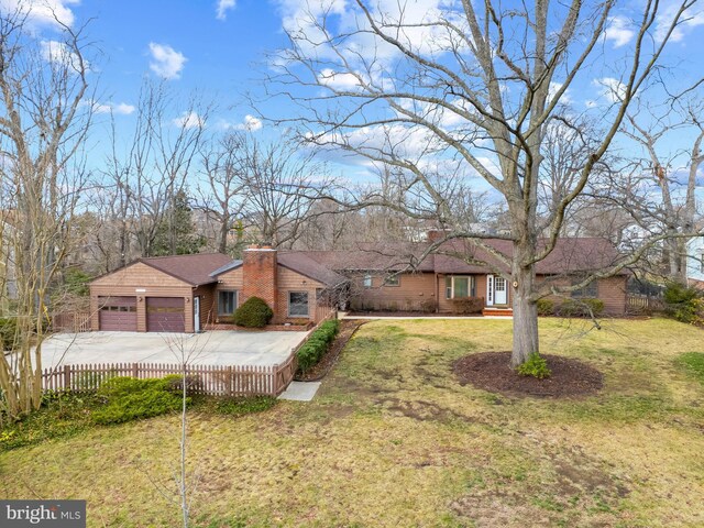 view of front of house with a chimney, concrete driveway, an attached garage, fence, and a front lawn