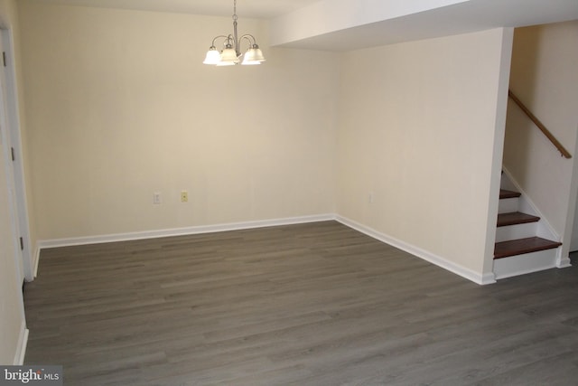 spare room with dark hardwood / wood-style floors and a notable chandelier