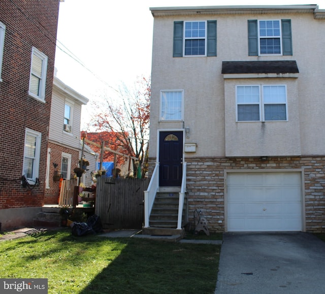 townhome / multi-family property with a front lawn and a garage