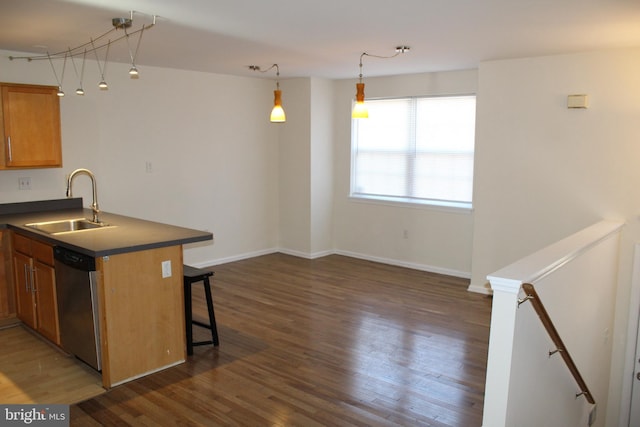 kitchen with pendant lighting, dishwasher, sink, dark hardwood / wood-style floors, and a breakfast bar area