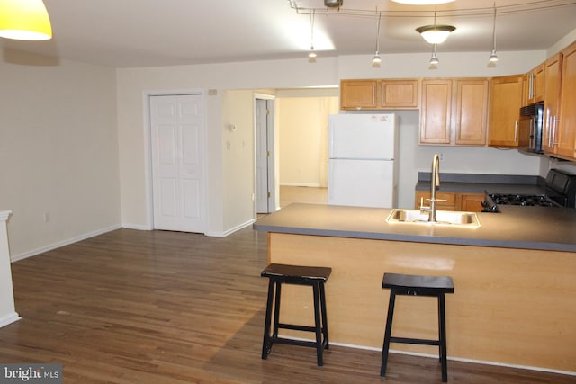 kitchen featuring a breakfast bar area, stove, hanging light fixtures, white refrigerator, and sink