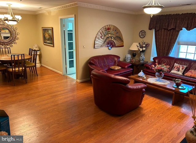 living room with crown molding, wood-type flooring, and an inviting chandelier