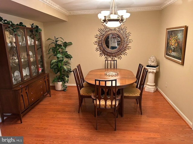 dining space with an inviting chandelier, crown molding, and light wood-type flooring