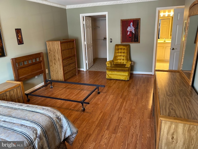 bedroom featuring wood-type flooring, connected bathroom, sink, and a spacious closet