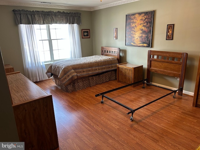 bedroom with wood-type flooring and ornamental molding