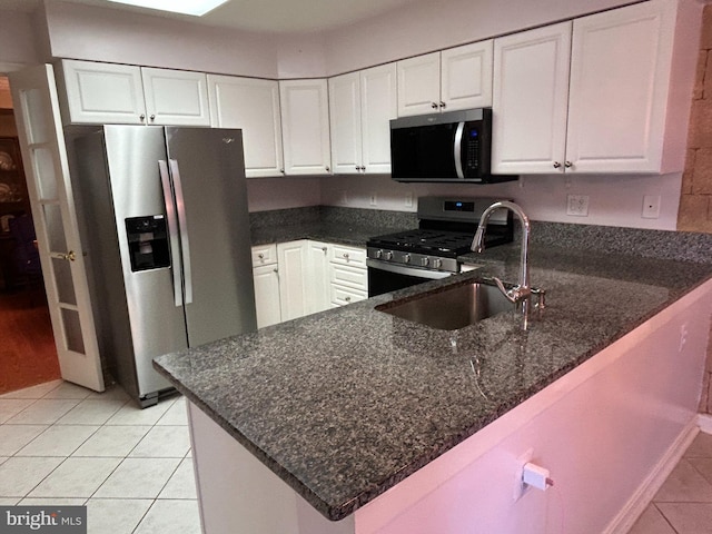 kitchen featuring sink, white cabinetry, dark stone countertops, kitchen peninsula, and stainless steel appliances