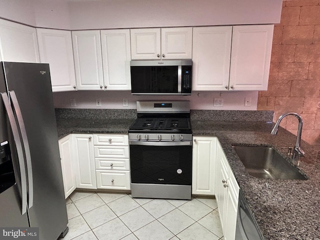 kitchen with sink, dark stone counters, white cabinets, and appliances with stainless steel finishes