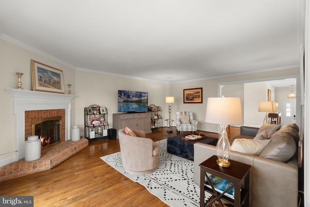 living room with a brick fireplace, wood-type flooring, and crown molding