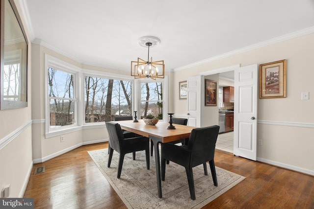 dining room with crown molding, a chandelier, and hardwood / wood-style flooring