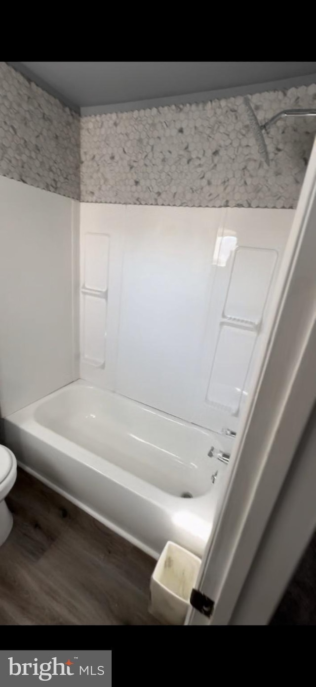 bathroom with bathtub / shower combination, hardwood / wood-style floors, and toilet