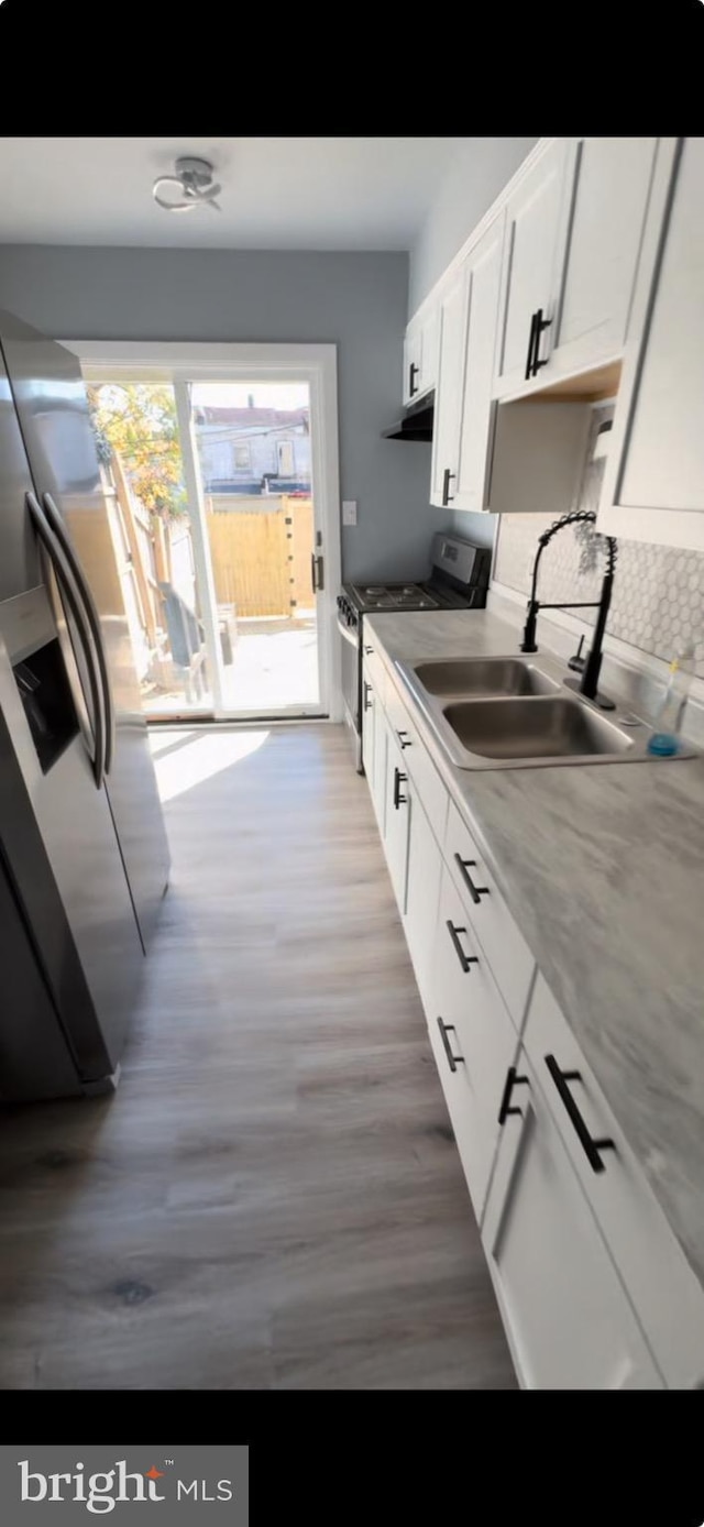 kitchen featuring light stone countertops, hardwood / wood-style floors, white cabinetry, stainless steel appliances, and sink