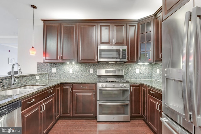 kitchen with sink, appliances with stainless steel finishes, hanging light fixtures, backsplash, and light stone countertops