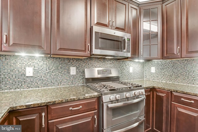 kitchen featuring appliances with stainless steel finishes, light stone countertops, and backsplash