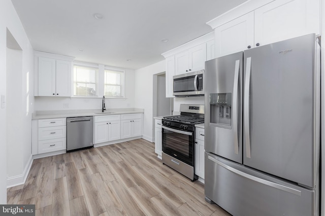 kitchen with light hardwood / wood-style flooring, sink, stainless steel appliances, and white cabinetry