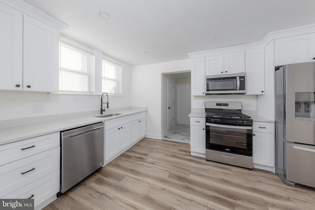 kitchen with sink, white cabinetry, light hardwood / wood-style flooring, and stainless steel appliances