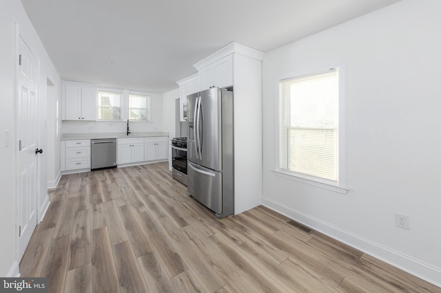 kitchen featuring sink, white cabinetry, appliances with stainless steel finishes, and light wood-type flooring