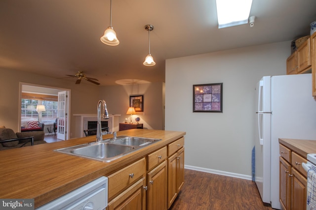 kitchen featuring decorative light fixtures, dark hardwood / wood-style floors, sink, white appliances, and wood counters