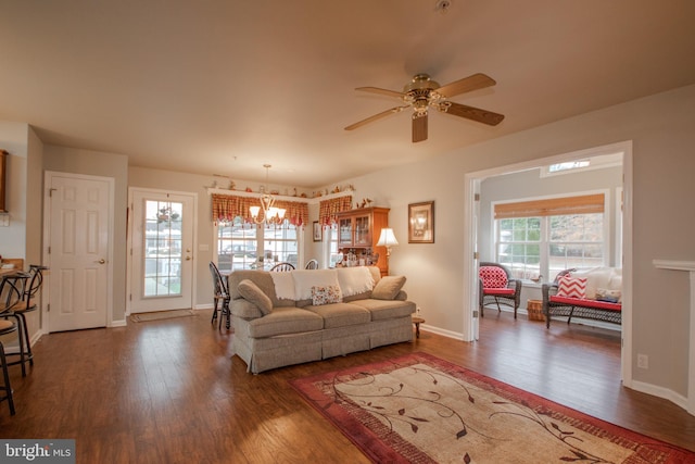 living room featuring ceiling fan with notable chandelier and dark wood-type flooring