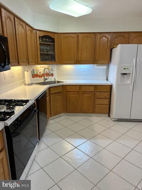 kitchen featuring black appliances, backsplash, and sink