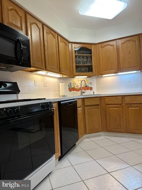 kitchen with decorative backsplash, sink, black appliances, and light tile patterned flooring