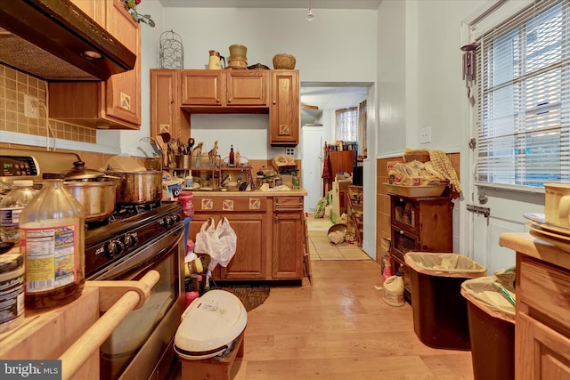 kitchen featuring plenty of natural light, extractor fan, light hardwood / wood-style floors, and range