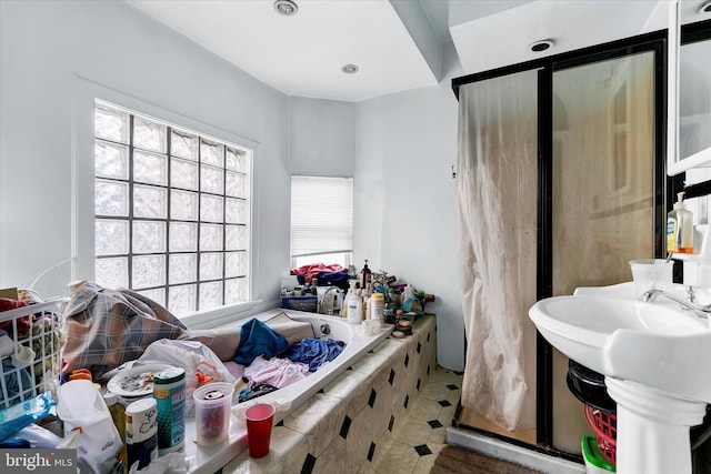 bathroom with tile patterned flooring, sink, and tiled tub