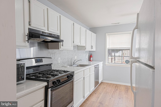 kitchen with stainless steel appliances, sink, decorative backsplash, and white cabinets