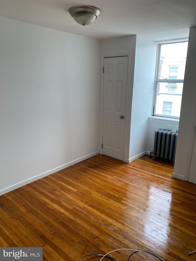 empty room featuring radiator heating unit and light hardwood / wood-style flooring