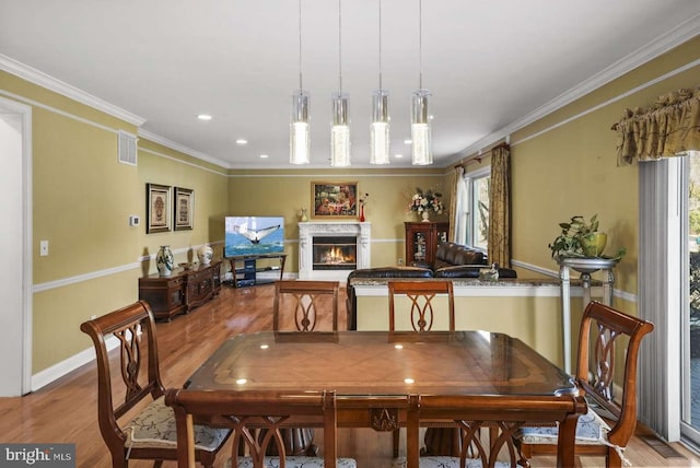 dining room featuring a wealth of natural light, crown molding, and light hardwood / wood-style floors