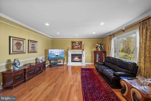 living room featuring a high end fireplace, light hardwood / wood-style flooring, and crown molding