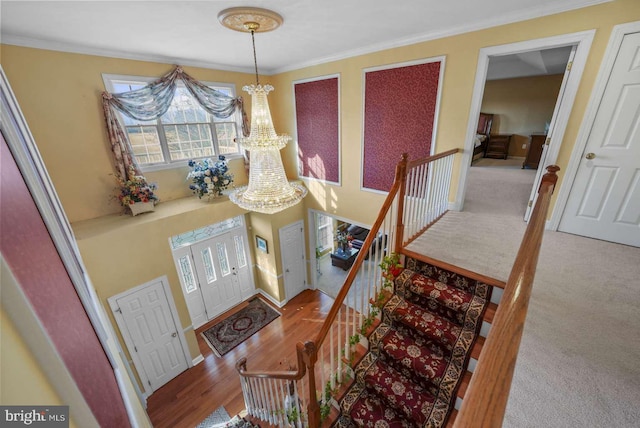 entrance foyer with wood-type flooring, a notable chandelier, and crown molding