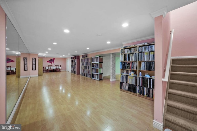 exercise area with ornamental molding and light hardwood / wood-style floors