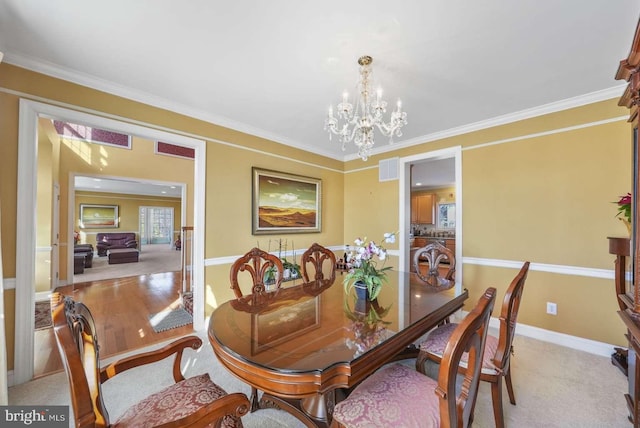 dining space featuring an inviting chandelier, crown molding, and light hardwood / wood-style flooring