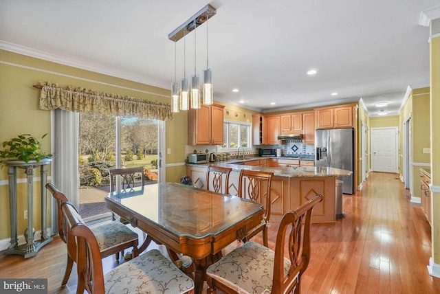 dining space with a notable chandelier, sink, crown molding, and light hardwood / wood-style flooring