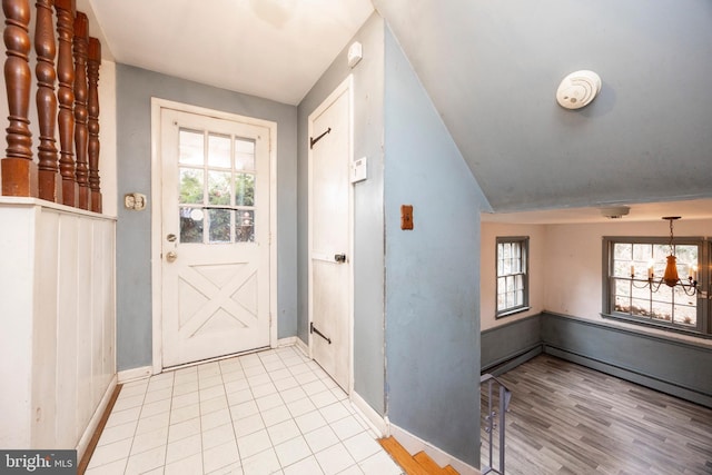 doorway to outside featuring an inviting chandelier, light tile patterned floors, and plenty of natural light