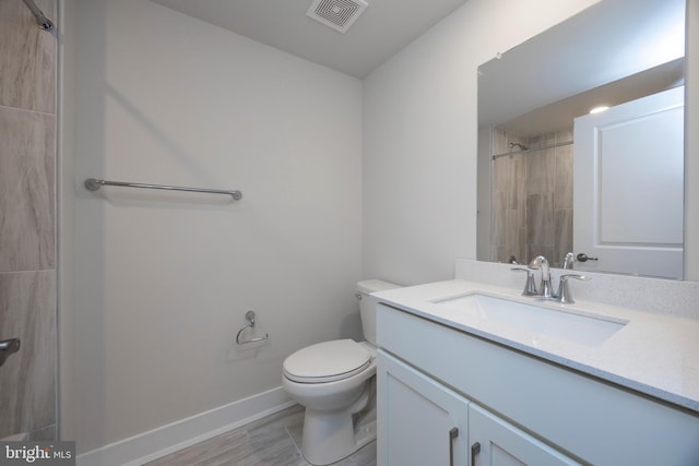 bathroom with vanity, tiled shower, and toilet