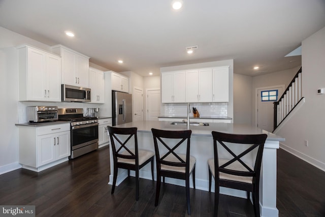 kitchen featuring white cabinetry, appliances with stainless steel finishes, an island with sink, and a kitchen breakfast bar