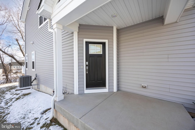 snow covered property entrance featuring central AC unit